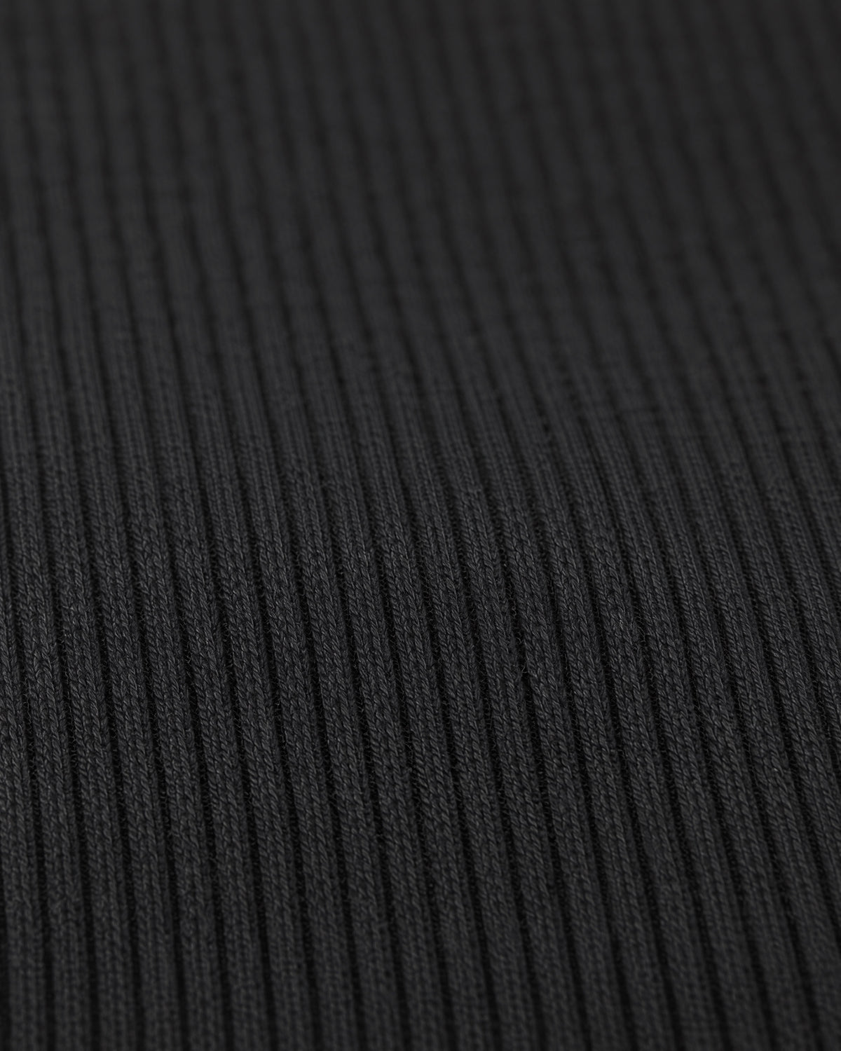Close view of TIIN BABY TEE fine black ribbed cotton fabric.